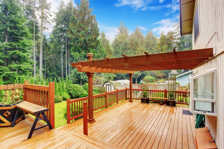 An image of a deck with pergola and bench on the back of a house.