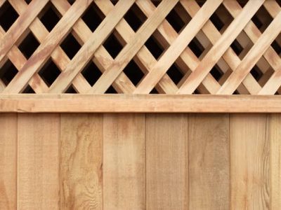 A light brown pine wooden fence with lattice on the top for added decoration.